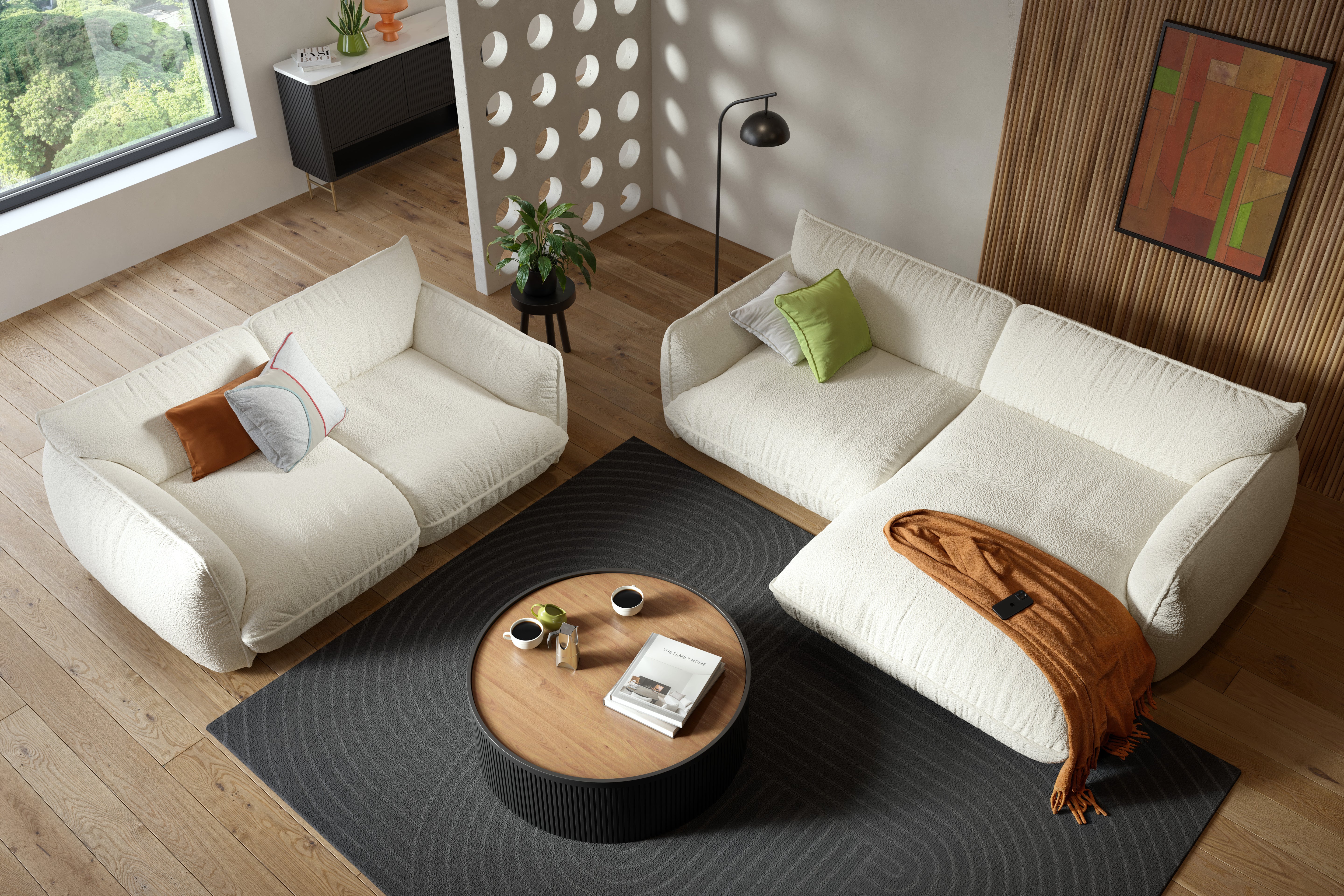 Modernes Wohnzimmer mit zwei weißen Sofas, rundem Couchtisch und dekorativen Kissen und Überwürfen.